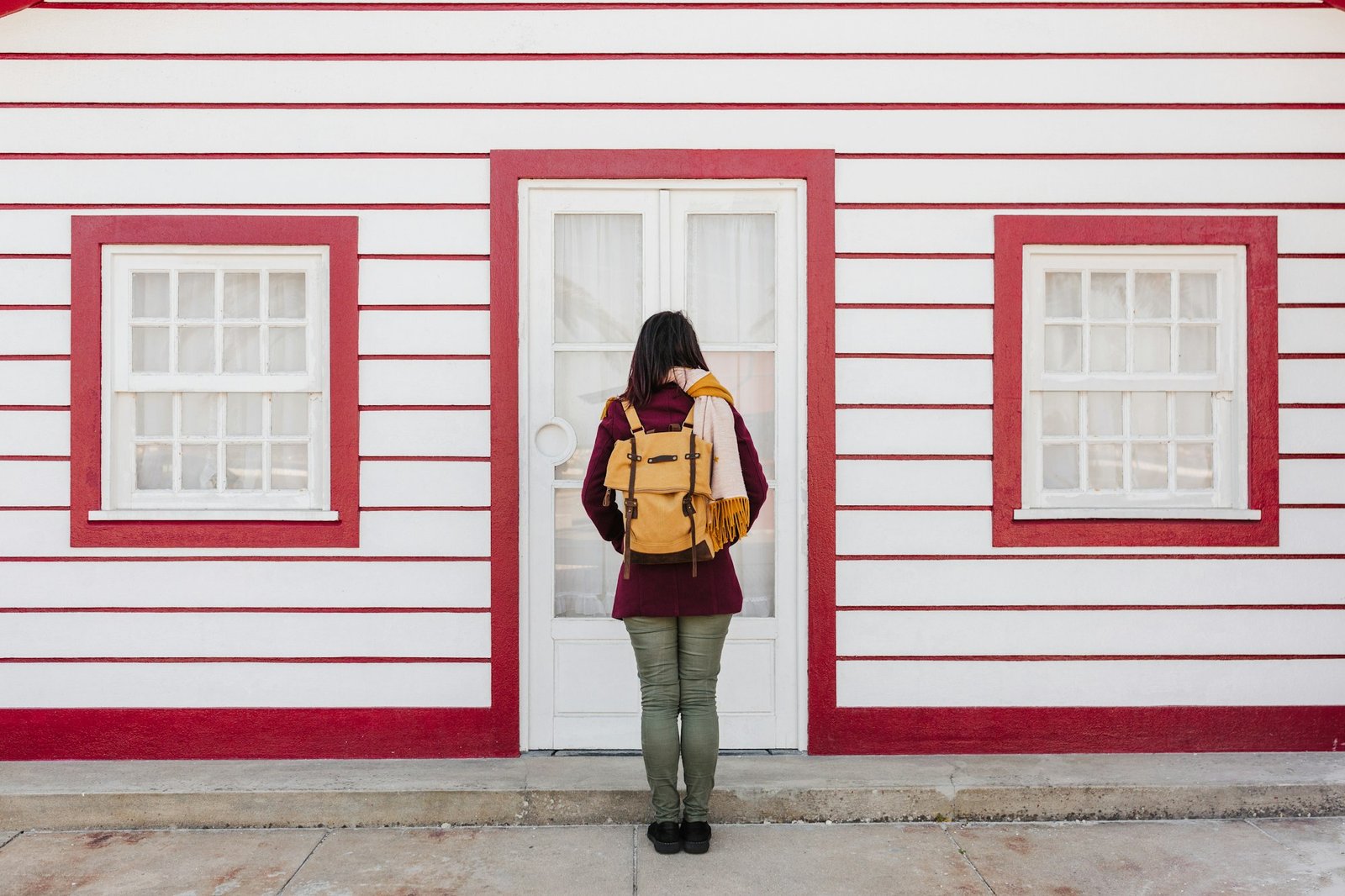 back view of backpacker woman in front of colorful houses.promenade of Costa Nova, Aveiro, Portugal