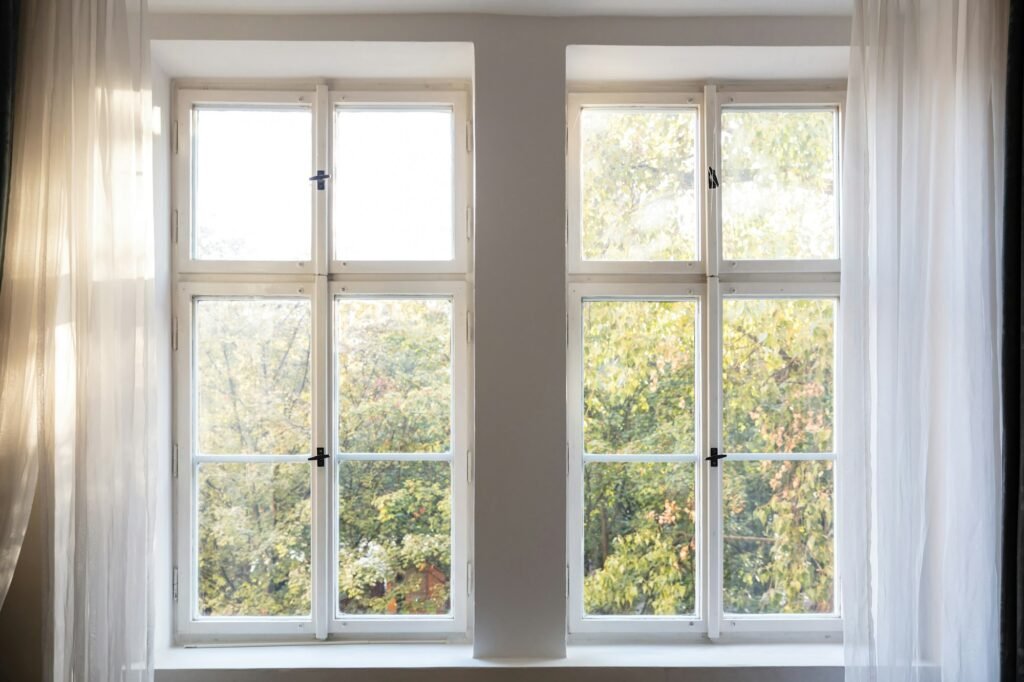 Fall season. Trees with autumn leaves out of two closed white wooden windows.