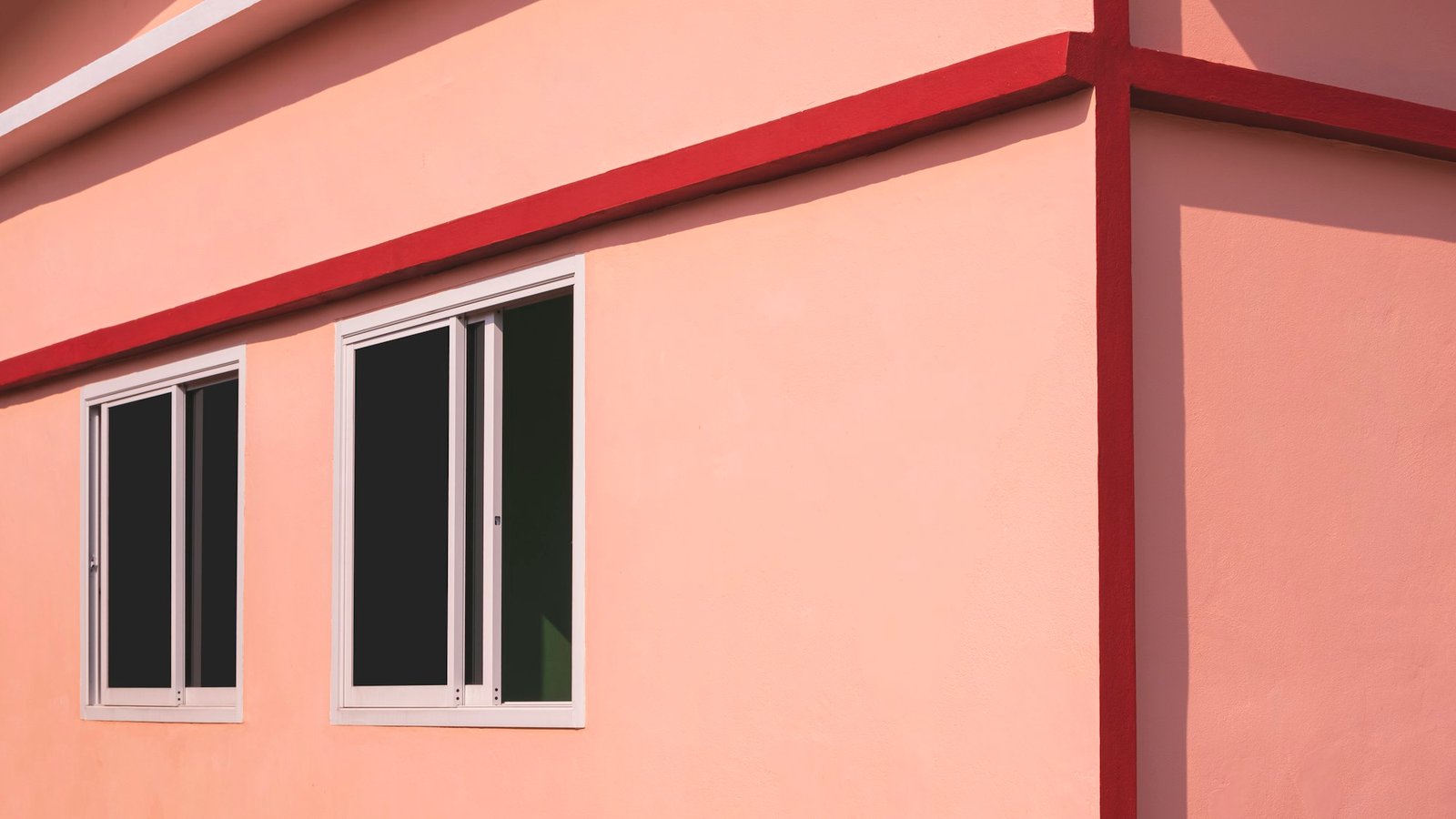 Sunlight on surface of glass sliding windows on orange concrete wall of modern house